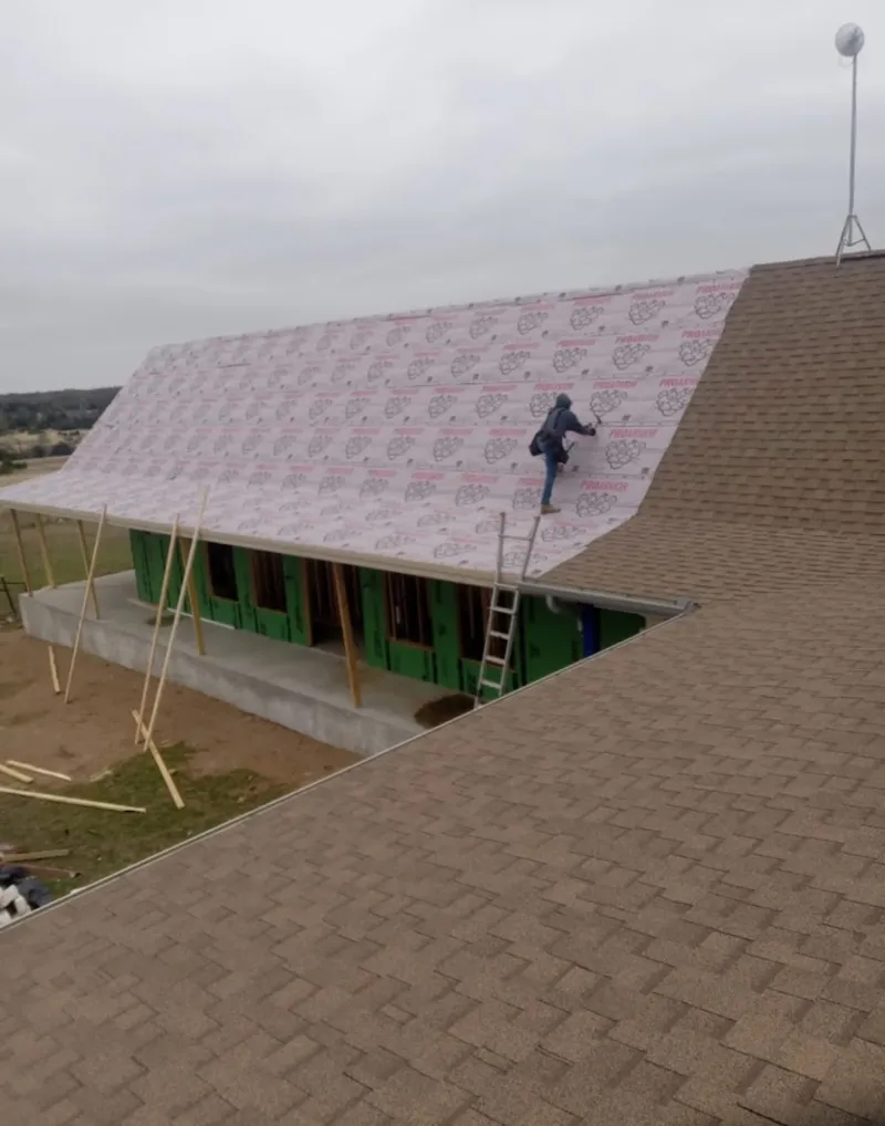 Worker preparing underlayment for a metal roof installation in Clarksburg